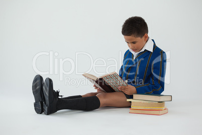 Schoolboy reading book on white background