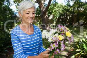 Smiling senior woman holding fresh flower bouquet
