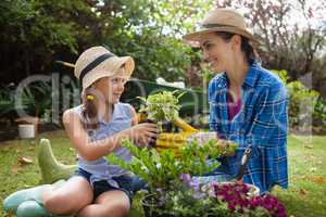 Smiling daughter and mother with potted plants