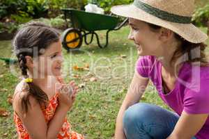 Smiling mother and daughter talking on field