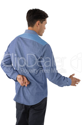 Rear view of businessman extending arm for handshake with fingers crossed