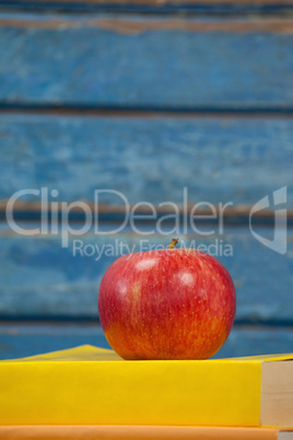 Stack of books and apple against blue wooden background