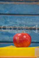 Stack of books and apple against blue wooden background