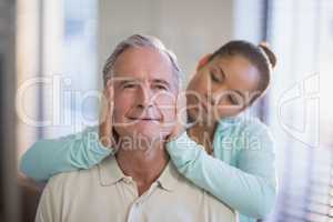 Female therapist holding head of senior male patient