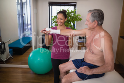 Smiling female therapist holding hand of senior male patient