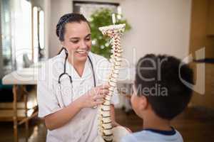 Smiling young female therapist explaining boy about spine