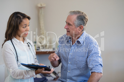 Female therapist and senior male patient discussing file