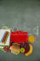 School supplies and lunch box arranged on chalkboard