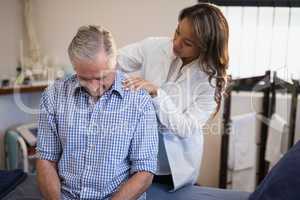 Female therapist examining neck of male patient