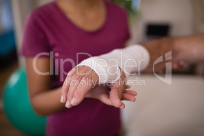 Close-up of senior male patient with bandage on wrist by female therapist