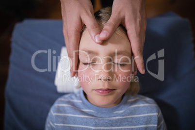 Overhead view of boy receiving head massage from female therapist