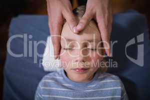 Overhead view of boy receiving head massage from female therapist