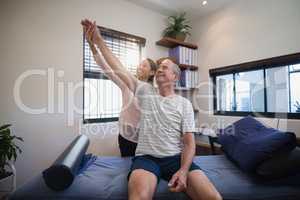 Smiling female doctor and male patient looking up with arms raised