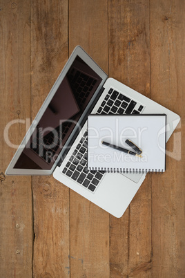 Laptop, pen, and diary on wooden background