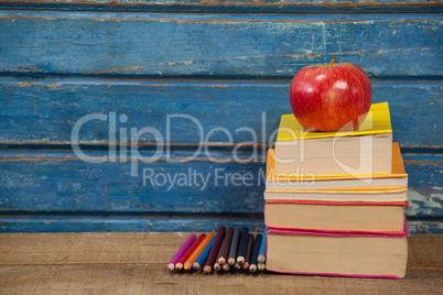 Stack of books, apple and color pencils