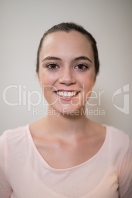 Close-up portrait of smiling young female therapist against wall