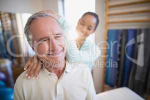 Smiling senior male patient receiving neck massage from female therapist