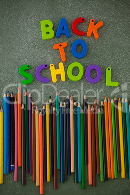 Block letters and color pencils arranged on chalkboard