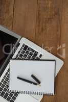 Laptop, pen, and diary on wooden background