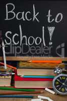 Alarm clock, pencils, chalk, books and slate with back to school text