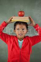 Young girl balancing books and apple on her head