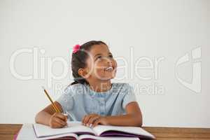 Young girl writing in her book against white background