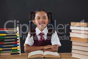 Schoolgirl reading a book against chalkboard