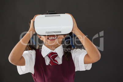 Schoolgirl using virtual reality headset against blackboard