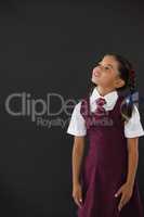 Schoolgirl standing against blackboard in classroom