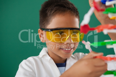 Schoolboy experimenting molecule model in laboratory