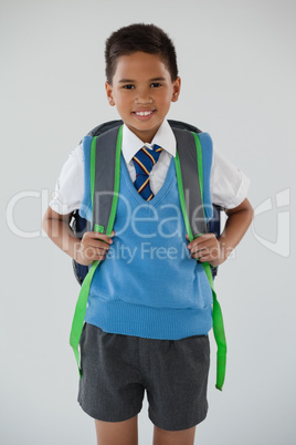 Schoolboy in school uniform with school bag on white background