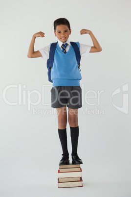 Schoolboy standing on books stack against white background