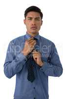 Portrait of young businessman adjusting necktie
