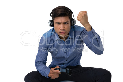 Businessman with fist wearing headphones while playing video game