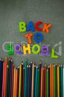Block letters and color pencils arranged on chalkboard