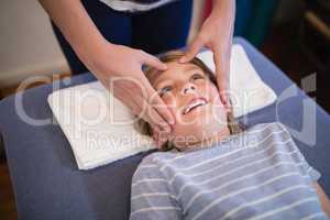 High angle view of smiling boy receiving massage from female therapist