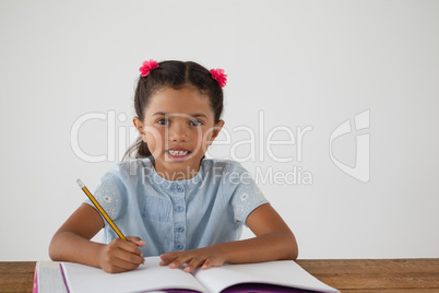 Young girl writing in her book against white background