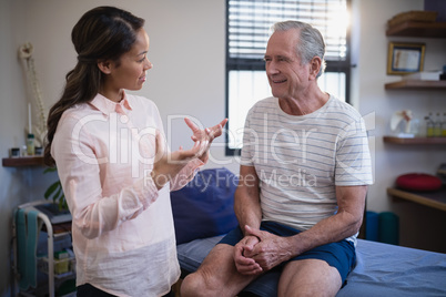 Senior male patient looking at female therapist gesturing while talking