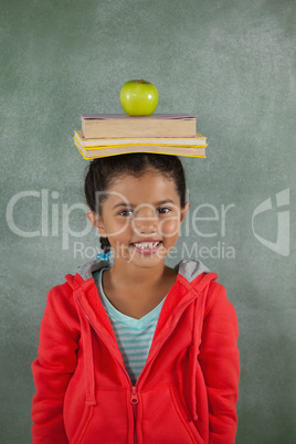 Young girl balancing books and apple on her head