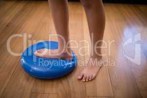 Low section of boy standing while stepping on large blue stress ball