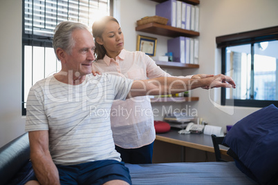 Female doctor and senior male patient looking at hand