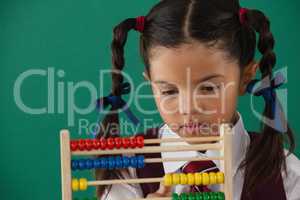 Schoolgirl using abacus against chalkboard