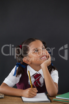 Schoolgirl doing her homework against chalkboard