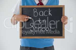 Schoolboy holding writing slate with text back to school against white background