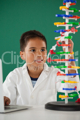 Smiling schoolboy experimenting molecule model in laboratory