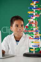 Smiling schoolboy experimenting molecule model in laboratory