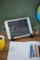 Digital tablet and globe on table in classroom