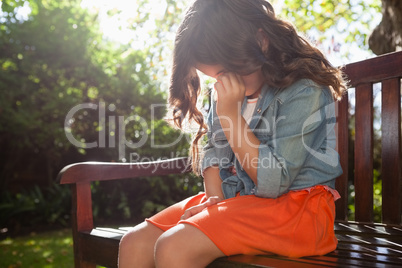 Upset girl crying while sitting on wooden bench