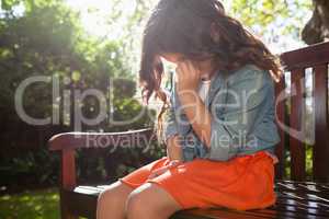 Upset girl crying while sitting on wooden bench