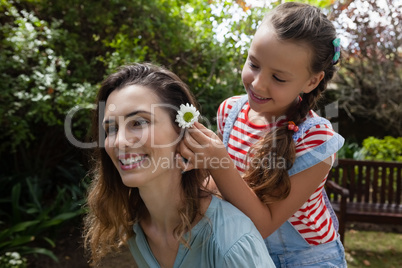 Girl positioning white flower in hair of mother